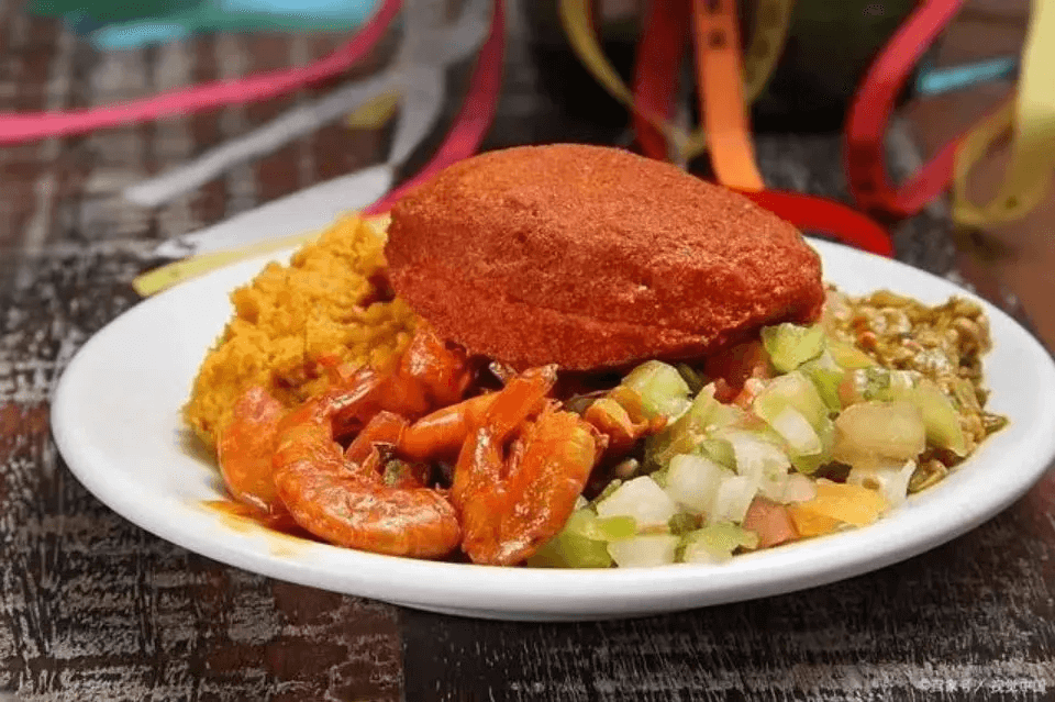 這是一盤傳統巴西美食阿卡茄，搭配著蝦仁、蔬菜和米飯，色彩鮮豔。