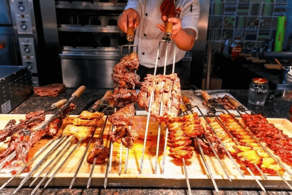 一位廚師在準備巴西烤肉，多種肉類串掛在烤架上。