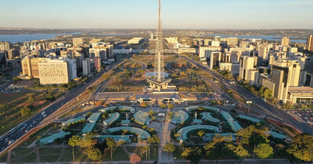 該圖片展示了巴西首都巴西利亞市中心的獨特建築布局與景觀,中央電視塔成為視覺焦點,四周被現代建築與公園環繞,遠處的湖泊增添了自然之美,展現了巴西利亞作為現代城市規劃典範的魅力。